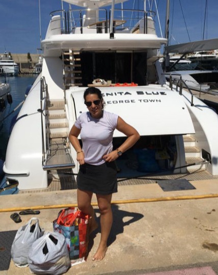 A woman with bags of donations behind a yacht on a dock