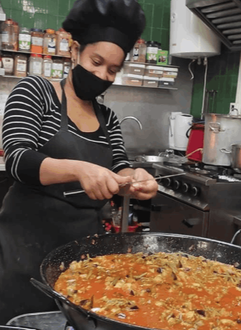 A chef cooking a large pot of food at the soup kitchen