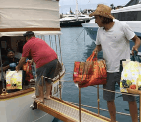 Yacht crew moves bags of donations across the passerelle of the yacht