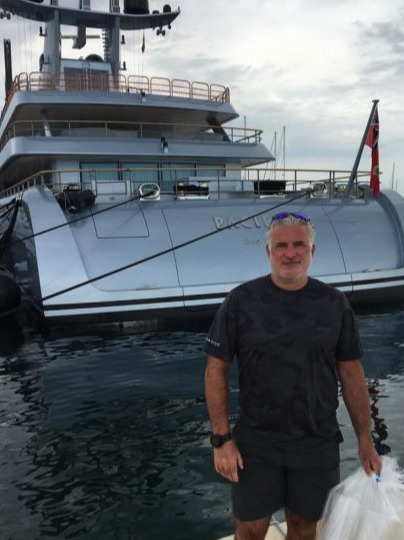 A man with bags of donations standing behind a motor yacht