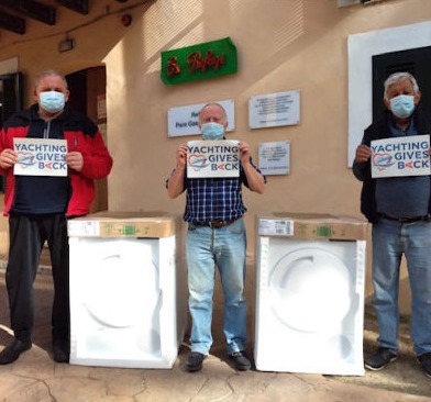 Three men holding logos of YGB next to two donated washing machines