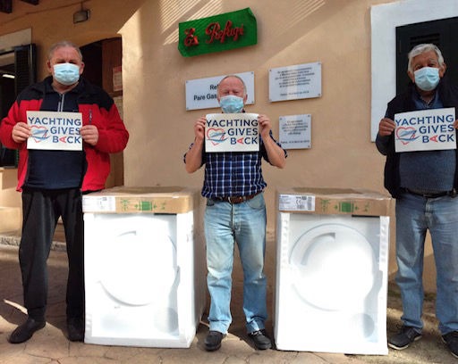 Three men holding YGB logos next two donated washing machines