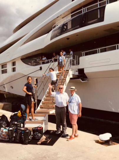 A group of people next to a side passerelle of a large motor yacht