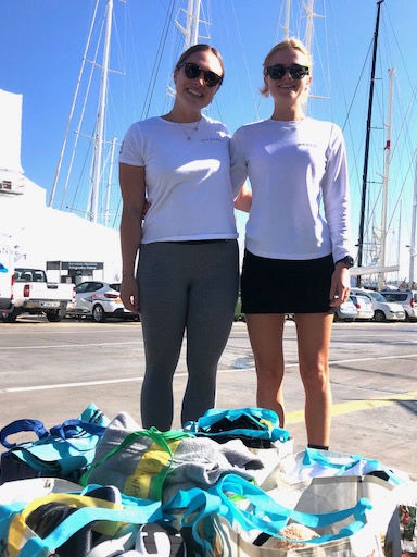 Two women standing on dock with bags of donations
