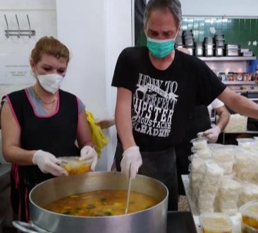 Big pot of soup being prepared by two volunteers