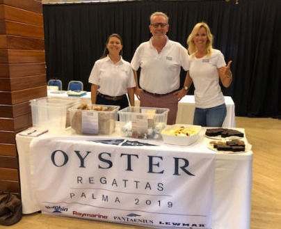A man and two women standing next to donated food from a regatta