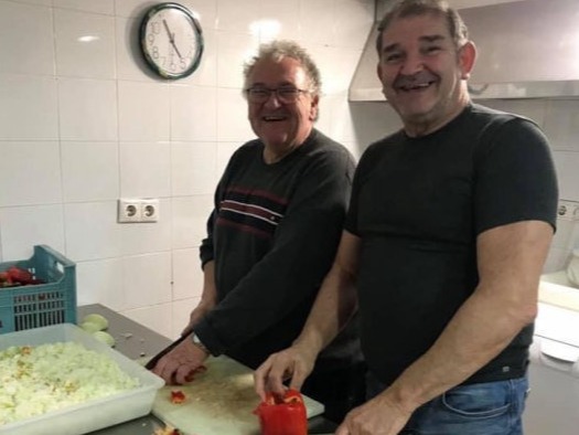 Two smiling men cutting vegetables in the kitchen