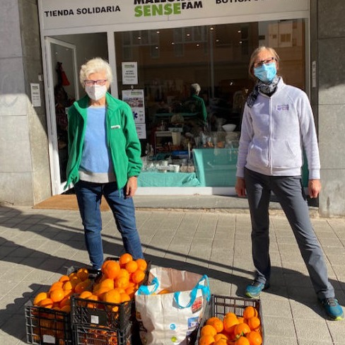 Two women showing a large donation of oranges