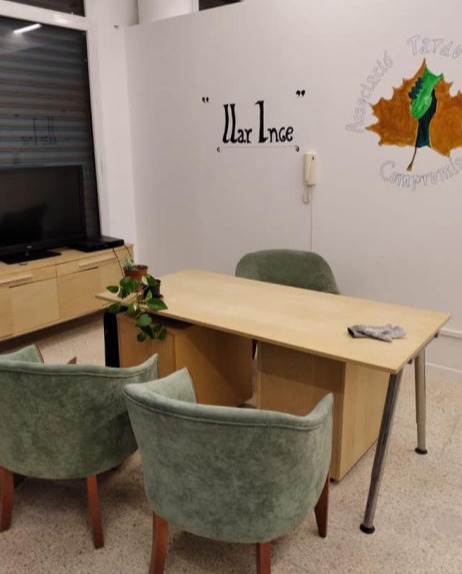 A wooden desk and green chairs around it