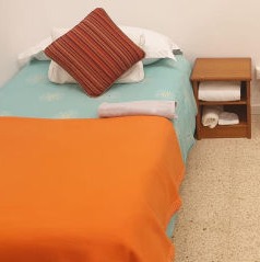 A neatly made bed in  dormitory at the shelter Llar Inge
