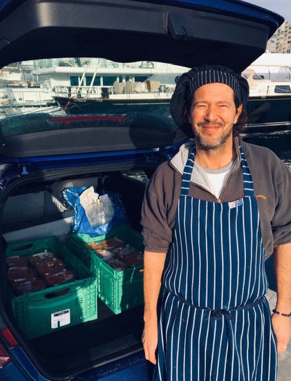 A chef standing behind an open boot of a car