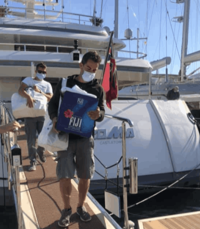 Yacht crew carries bags of donations across the passerelle of the yacht