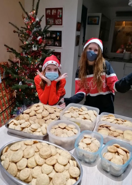 Two girls with Santa hats and boxes of cookies